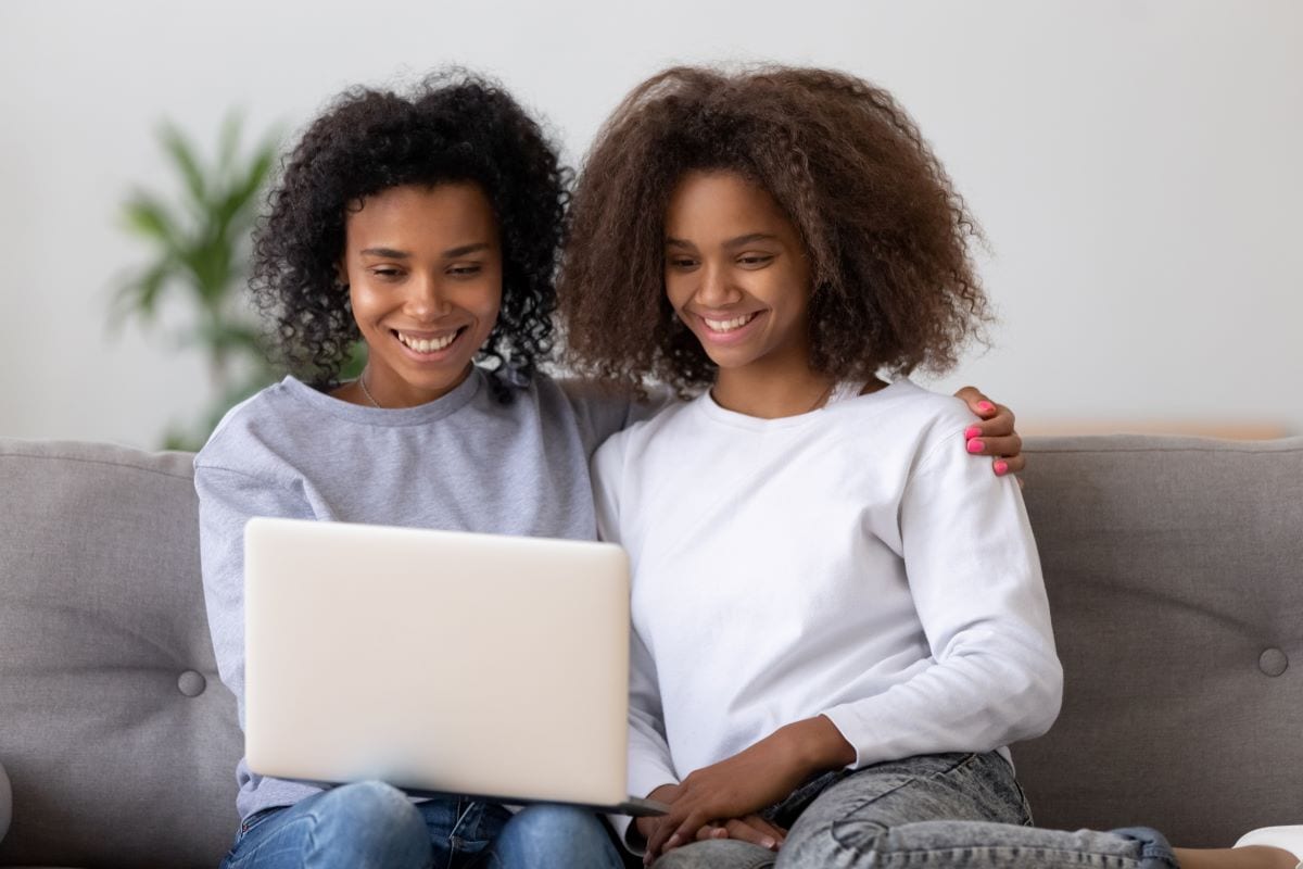 Une mère et sa fille regardent les travaux scolaires de leur fille sur un portfolio numérique.